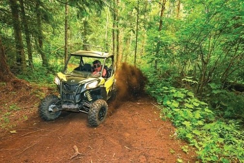 a truck driving down a dirt road in a forest